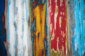 Old grungy and weathered colourfully painted wooden wall plank texture in yellow, blue, red and white mix of colours as artistic background.