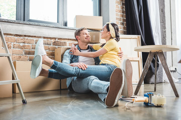 loving young couple sitting on floor together while moving into new home