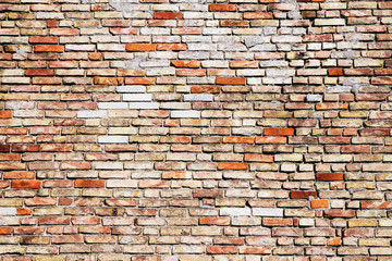 Old and weathered grungy yellow and red brick wall with visible crack as rustic rough texture background.