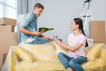 interracial happy couple drinking champagne after moving into new home