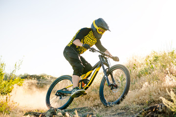 Obraz premium Cyclist Riding the Mountain Bike on the Summer Rocky Trail at the Evening. Extreme Sport and Enduro Cycling Concept.