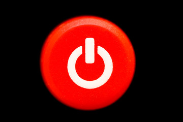 Round bright red power (on and off) button or switch with white power symbol macro photography and...
