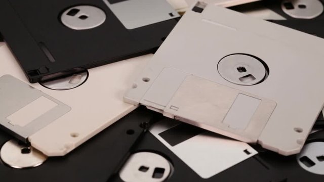 3.5 inch computer floppy disks scattered on a flat surface - vintage technology, closeup, slide above
