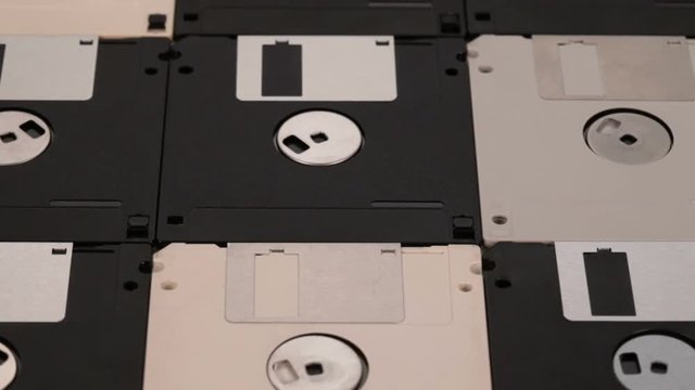 Many 3.5 inch computer floppy disks neatly arranged on a flat surface - vintage technology, closeup, slide above