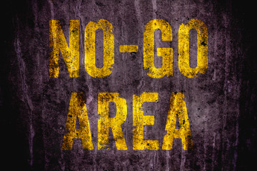 “No-Go Area” warning sign in yellow letters painted over dark grungy concrete wall texture background. Sign as concept for: do not enter the area, caution, danger or off limits in violent urban areas