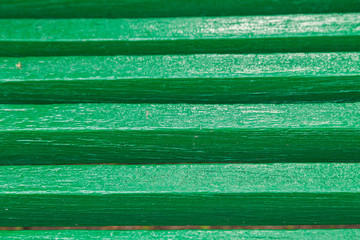 Details of a green bench, background of boards painted in green color.