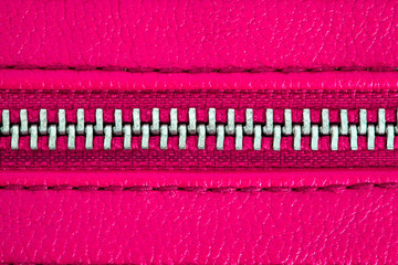 Pink zipper tightly closed binding together two layers of fabric textile and leather under high...