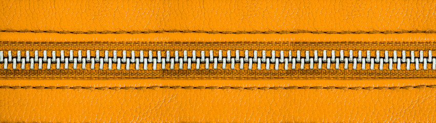 Yellow zipper tightly closed binding together two layers of fabric textile and yellow leather under high magnification close detail photography as wide panorama texture background banner.