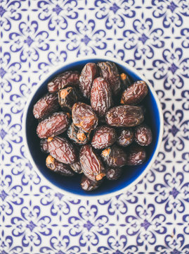 Traditional muslim food for Ramadan iftar meal. Dates over typical oriental ornamental painted background, top view