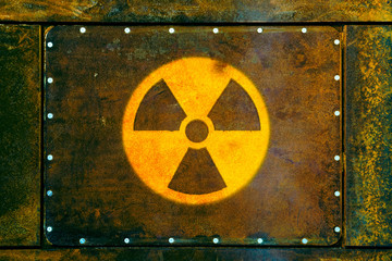 Round yellow radioactive (ionizing radiation) danger warning symbol painted on a massive rusty...