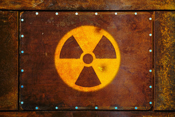 Round yellow radioactive (ionizing radiation) danger warning symbol painted on a massive rusty...