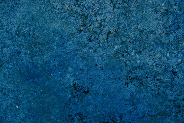 Vivid bright blue color facade stone wall with imperfections and cracks as an empty rustic and simple background texture space.