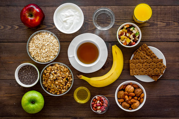 Set of products for healthy vegetarian breakfast. Fruits, oatmeal, yogurt, nuts, crispbreads, chia on dark wooden background top view