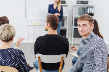 Young man smiling at camera during office meeting
