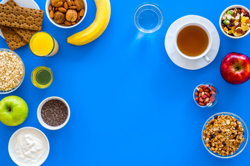 Make a menu for wholesome breakfast. Fruits, oatmeal, yogurt, nuts, crispbreads, chia on blue background top view copy space