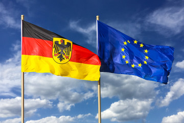 Flags of Germany (Federal Republic of Germany; in German: Bundesrepublik Deutschland) and the European Union (EU) waving in the wind on a bright sunny summer day and blue sky background.
