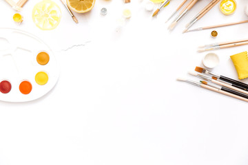 Creative flat lay art workspace with yellow palettes, paint brushes,. Artist background