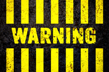 Warning sign with yellow and black stripes painted over cracked concrete wall coarse texture...