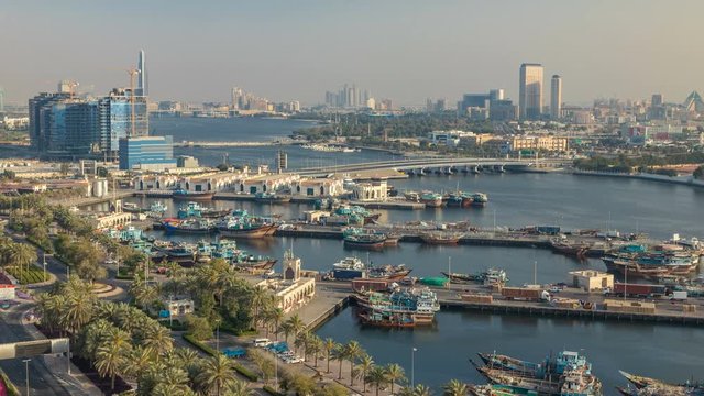 Dubai creek landscape timelapse with boats and ship in port and modern buildings in the background during sunset