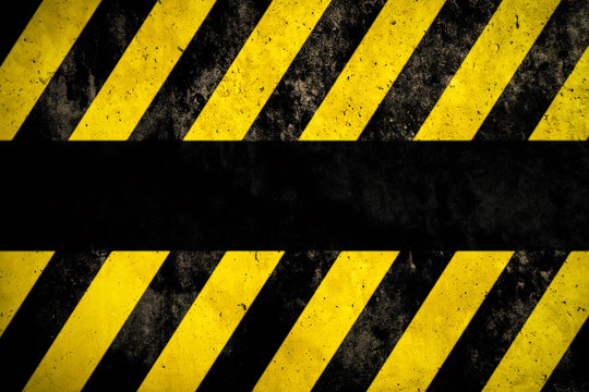 Warning background with yellow and dark stripes painted over concrete wall facade texture and empty space for text message in the middle. Concept image for caution, danger and hazard.