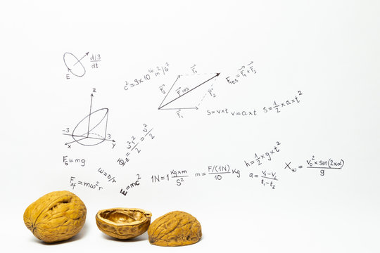 Concept of the phrase physics in a nutshell. Physics formulas drawn on white paper with walnuts