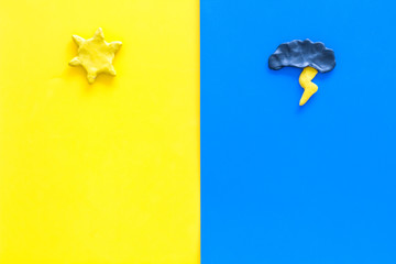 Good and bad weather concept. Template for forecast. Sun vs cloud and lightening on yellow and blue background top view copy space