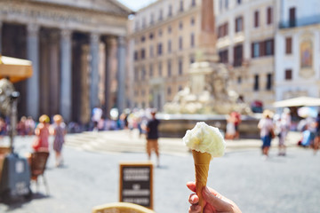 Crop hand holding cone with delectable ice cream on blurred background of square near Pantheon in Rome, Italy
