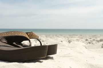 Obraz na płótnie Canvas Flip flops in the sand on sea beach background