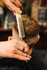 Hairdresser blow drying his client in barbershop. Barber using scissors and comb