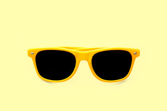 Summer yellow sunglasses isolated in pastel yellow background. Minimal concept image for sun protection, hot days, tropical travel, summer vacations and beach holidays.