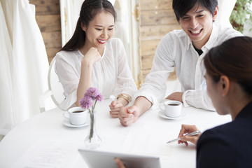 ウエディングプランナーと結婚式の相談をする幸せそうな夫婦