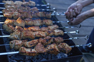 fragment of cooking barbecue in nature with a hands of the cook close-up