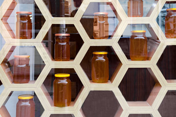 Blurred image, view through the glass of wooden shop window with glass jars with honey.