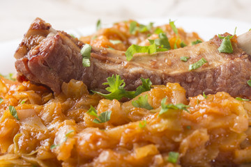 Portion of cabbage with smoked pork meat on plate