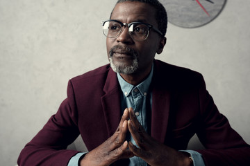 portrait of pensive mature african american man in eyeglasses and burgundy jacket - Powered by Adobe
