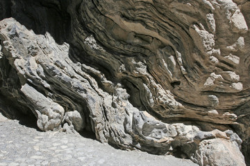 The high beautiful steep rocky slope of the gorge with wavy folds on the sunny day.