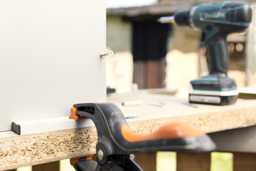 Furniture assembly. Making of kitchen cabinet using screwdriver, construction clamp and screws