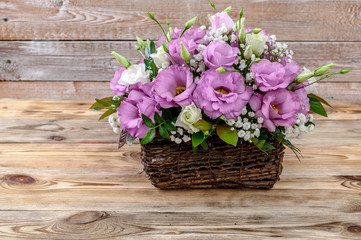 Bouquet of flowers in a basket on a wooden background.