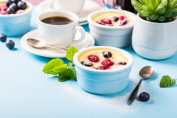 Berry clafouti. Traditional french sweet fruit dessert clafoutis with raspberries and blueberries on blue background. Healthy gluten free food concept with copy space.