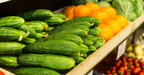 Ripe cucumbers are laid out in a box on a shelf in the grocery store.