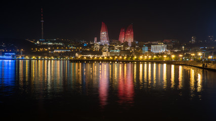 Baku night cityscape with flaming towers and reflections in the Caspian sea bay