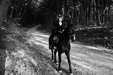 Fototapeta na wymiar Mystical girl in wreath wear in black at horse in wood.