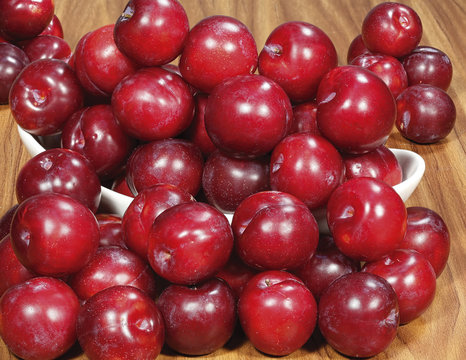 Red plums on old wooden background