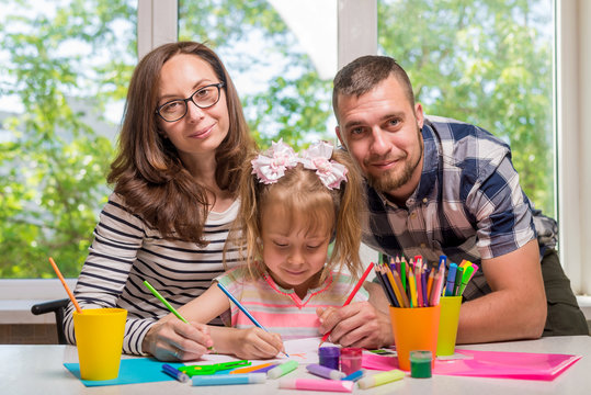Mom and Dad help their little girl do homework for school