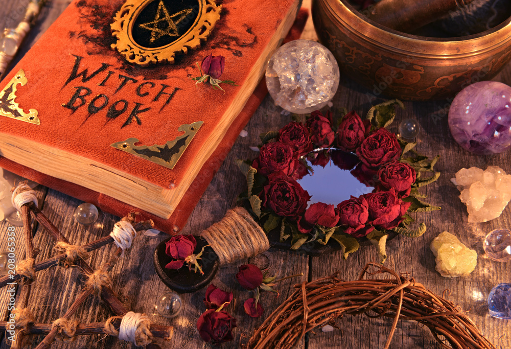 Wall mural Witch book with magic rose mirror, pentagram and mystic objects on planks. Occult, esoteric and divination still life. Halloween background with vintage objects 