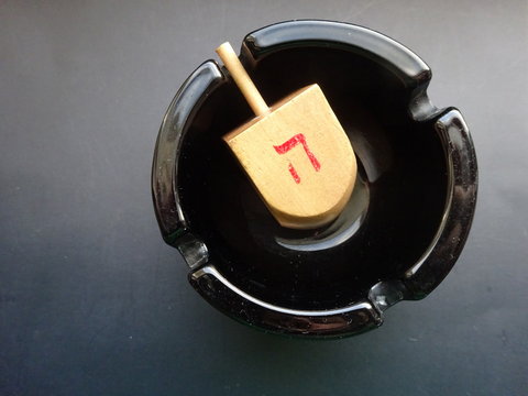Jewish wooden dreidl in a black ashtray