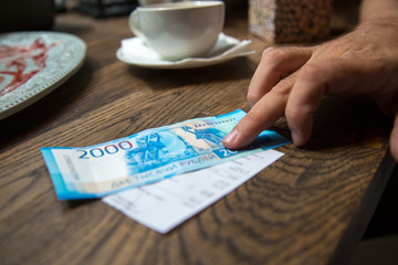 Fototapeta na wymiar New 2000 rubles banknote in mans hand in cafe.