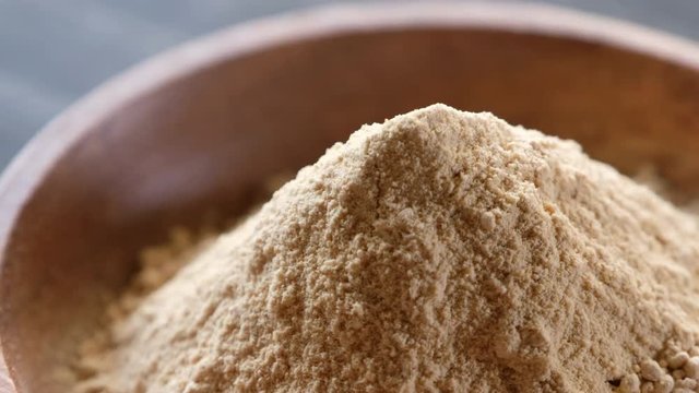 Rotating superfood maca powder in wooden bowl