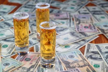 tequila gold on a background of randomly laid out the American dollars of different face value.