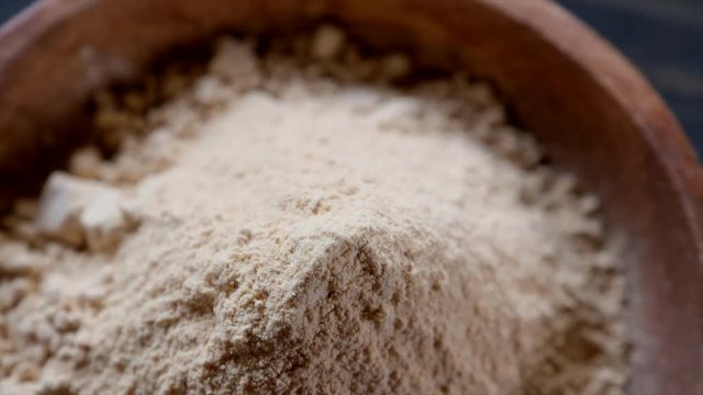 Rotating super food maca powder in wooden bowl